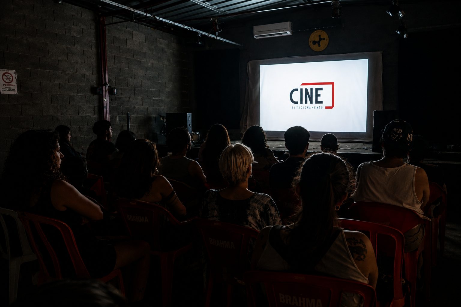 Plateia diante da tela com a marca do Cine Estacionamento